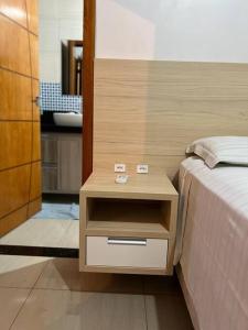 a bedroom with a bed and a nightstand next to a bed at Acomodação Três Fronteiras Foz in Foz do Iguaçu
