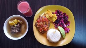 a yellow plate of food with rice and a bowl of fruit at Hotel Habitat Hospedaje in Bogotá