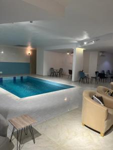 duży basen w hotelu z krzesłami i kanapą w obiekcie شقق جدة دستنيشن w mieście Dżudda