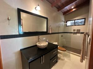 a bathroom with a sink and a toilet and a mirror at Villas Lambeau 3 Ocean View - 2BR 3 BA in Uvita