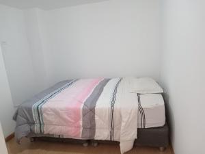 uma cama num quarto com uma parede branca em Departamento amoblado 9vno piso em Lima