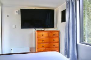 a bedroom with a dresser and a television on a wall at The Bird House Tiny Home in Ngaruawahia