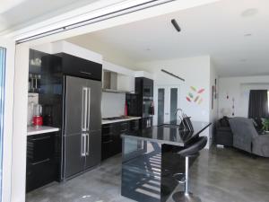 una cucina con armadi neri e frigorifero in acciaio inossidabile di Eagle View a Cable Bay