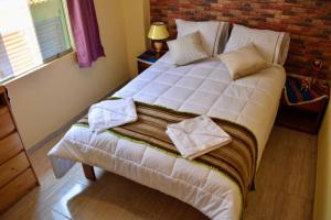 a white bed in a room with a brick wall at LA CUSQUEÑITA in Cusco