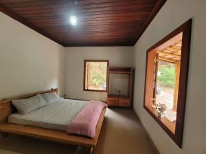 1 dormitorio con cama, techo de madera y ventana en Sítio Vale da Cachoeira, en Pôrto Firme