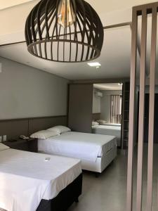 a bedroom with two beds and a chandelier at Garvey Hotel - Flat centro de Brasília in Brasilia