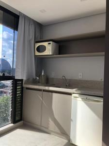a kitchen with a sink and a microwave at Garvey Hotel - Flat centro de Brasília in Brasilia