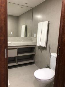 a bathroom with a toilet and a sink and a mirror at Garvey Hotel - Flat centro de Brasília in Brasilia