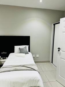 a bedroom with a large white bed with a black headboard at Coastal Bliss at Ongwe in Swakopmund