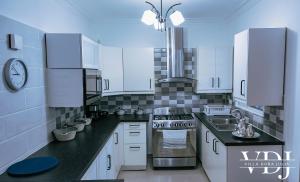 a kitchen with white cabinets and a stove top oven at Rooftop with Pool, La Romana, Villa Doña Julia in La Romana