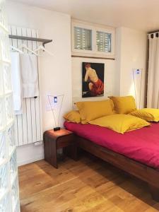 - une chambre avec un lit doté de draps rouges et d'oreillers jaunes dans l'établissement Petit luxe à la française - Paris Levallois à 15' des Champs Elysées, à Levallois-Perret