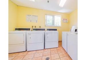 una fila de lavadoras y secadoras en una lavandería en Discover the Charm and the Sea Gardens, an Exceptional Gold Coast Studio Condo Retreat - Special Offer Now!, en Pompano Beach