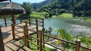 a balcony with a view of a river and a hut at Chácara Bela Vista in Paraibuna