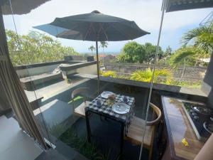 a balcony with a table and an umbrella at Bali Golden Elephant Boutique Villa in Jimbaran
