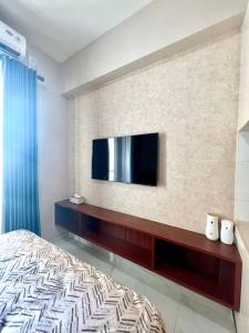 a bedroom with a bed and a tv on a wall at Livingatri - Skyhouse BSD next to AEON near ICE BSD in Cilandak
