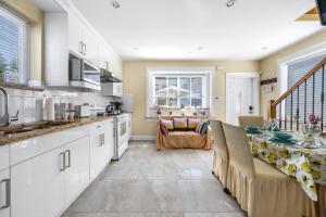 a kitchen with white cabinets and a table in it at Three bedrooms brand new laneway house near public transit in Vancouver