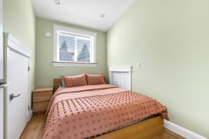 um quarto com uma cama com um edredão rosa em Three bedrooms brand new laneway house near public transit em Vancouver