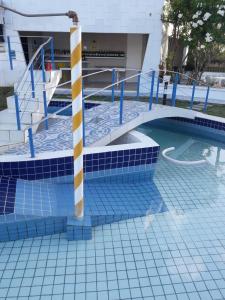 a swimming pool with blue and white tiles on the floor at Flat Beach Itamaracá - pousada FBI in Itamaracá