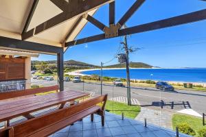 a porch with a wooden bench and a view of the ocean at Beach Duplex 72 Marine Dr - Fingal Bay in Fingal Bay
