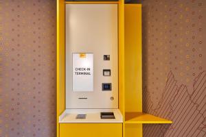 una máquina de venta de entradas amarilla y blanca en una habitación en McDreams Hotel Düsseldorf-City en Düsseldorf