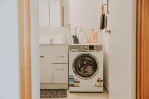 uma cozinha com uma máquina de lavar roupa numa cozinha branca em Finnview House em Hobart