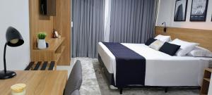 a bedroom with a bed and a desk with a lamp at Granja Brasil - Itaipava in Petrópolis +9 photos