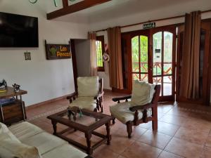 sala de estar con sofá, sillas y mesa en Cabañas Las Pencas en Mina Clavero