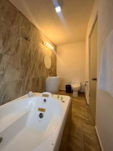 ein Badezimmer mit einer weißen Badewanne und einem WC in der Unterkunft AOHOM SANTUARIO HOTEL & SPA in Jiutepec