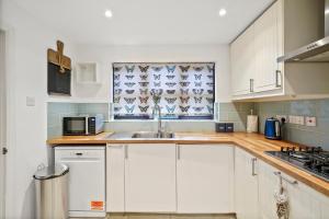 a kitchen with white cabinets and a sink at Beautiful 5 bedroom house in Stone, Aylesbury, Free parking in Stone