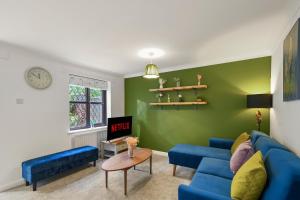 a living room with a blue couch and a green wall at Beautiful 5 bedroom house in Stone, Aylesbury, Free parking in Stone