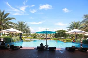 uma piscina num resort com pessoas sentadas sob guarda-sóis em Le Gia Villa 1, sang trọng, bên hồ, hướng biển, 3PN, 3 phòng tắm, Novaworld Phan Thiết cho kỳ nghỉ gia đình em Phan Thiet