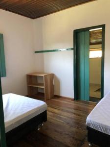 1 Schlafzimmer mit 2 Betten, einem Spiegel und einem Tisch in der Unterkunft Fazenda Vô Azarias in Visconde De Maua
