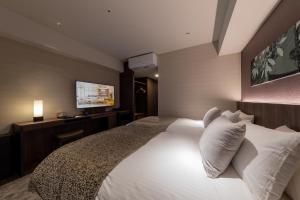 a bedroom with a white bed and a television at Iroha Grand Hotel Kintetsu Nara Ekimae in Nara