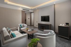 sala de estar con sillas blancas y TV en NATIONAL SCENIC SPOT SUNSHINE RESORT HOTEL, en Zhangjiajie