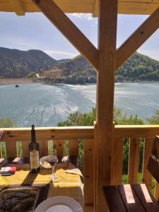Zaovine的住宿－Draganovi Konaci，阳台上的桌子上放着一瓶酒和一杯葡萄酒