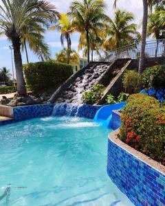 a swimming pool with a waterfall in a resort with palm trees at Aquatika Paraíso Tropical in Loiza