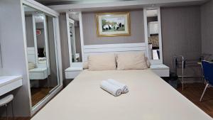 Cette chambre comprend un grand lit blanc et un miroir. dans l'établissement Studio28 Bassura Tower F East Jakarta -Min Stay 3 nights-, à Jakarta