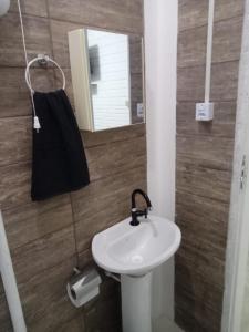 La salle de bains est pourvue d'un lavabo blanc et d'un miroir. dans l'établissement Hospedaria Mirante da maré ap4, à Imbituba