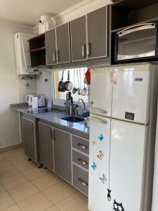 a kitchen with a white refrigerator and gray cabinets at C & N - Altos de la Bahía in El Calafate