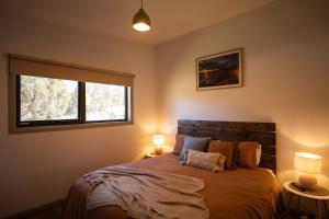 een slaapkamer met een bed met twee lampen en een raam bij Bush to Beach Getaway in Port Sorell