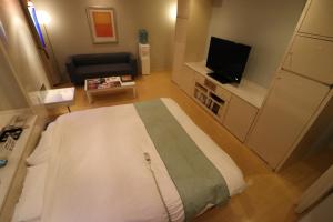 um pequeno quarto com uma cama e uma televisão em ホテルシエル em Himeji