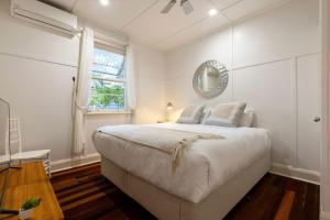 a white bedroom with a large bed and a mirror at A Perfect Stay Aaloka Bay in Byron Bay