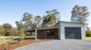 een huis met een garage en een grindoprit bij Bush to Beach Getaway in Port Sorell