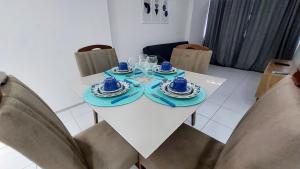 una mesa blanca con platos azules y vasos en ella en Apê com vista espetacular no Edif. Mr. Roterdam en Caruaru