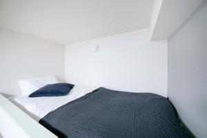 een witte slaapkamer met een bed met een blauw kussen bij リアル錦糸101 in Tokyo