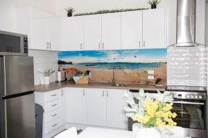 een keuken met witte kasten en een schilderij van een strand bij Bush to Beach Getaway in Port Sorell +17 foto's