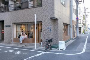 un couple assis dans une fenêtre de magasin dans une rue dans l'établissement リアル錦糸101, à Tokyo