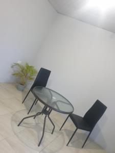 three chairs and a glass table in a room at Rooftop Inn Apartments in Piarco