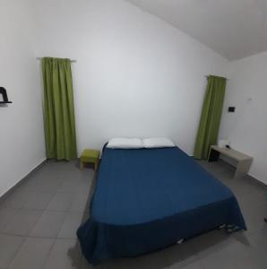 Schlafzimmer mit einem blauen Bett und grünen Vorhängen in der Unterkunft El Bonsai in Santiago del Estero