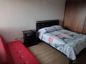 een kleine slaapkamer met een bed en een rode bank bij Disfruta de una vista hermosa. in Mosquera